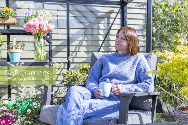 Femme assise dans une serre avec une tasse de thé