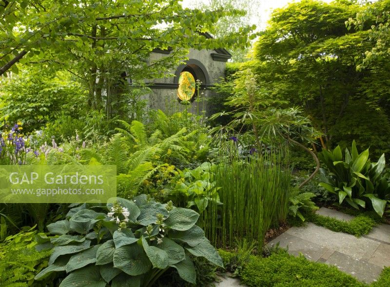 Un temple néo-classique entouré d'arbres et de plantes herbacées dans le Myeloma UK - A Life Worth Living Garden conçu par Chris Beardshaw au RHS Chelsea Flower Show 2023.