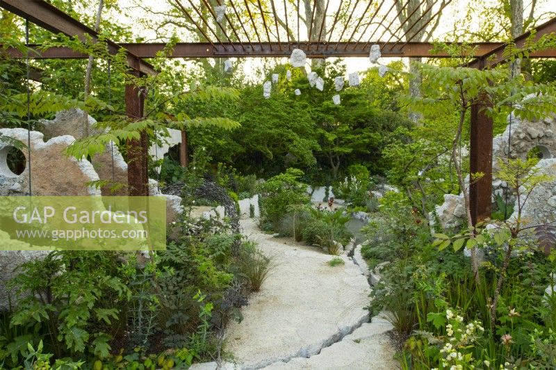 Des panneaux de béton et une grille métallique encadrent un sentier à travers les plantes vivaces dans les Samaritains' Listening Garden a Show Garden conçu par Darren Hawkes au RHS Chelsea Flower Show 2023