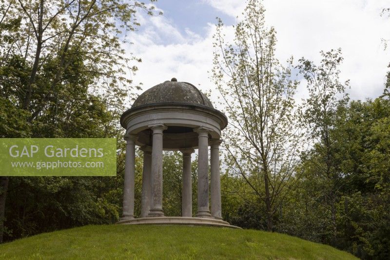 Un temple classique en forme de dôme sur une butte herbeuse. Trago Mills montrent les jardins, Devon, Royaume-Uni. Peut. Printemps