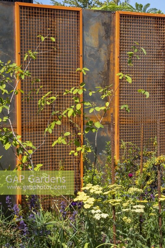 Grille de sécurité orange recyclée réutilisée comme élément de délimitation avec plantation devant - The 3D Gardener Path of Renewal - BBC Gardeners' World Live 2023, NEC Birmingham - Designer David Negus