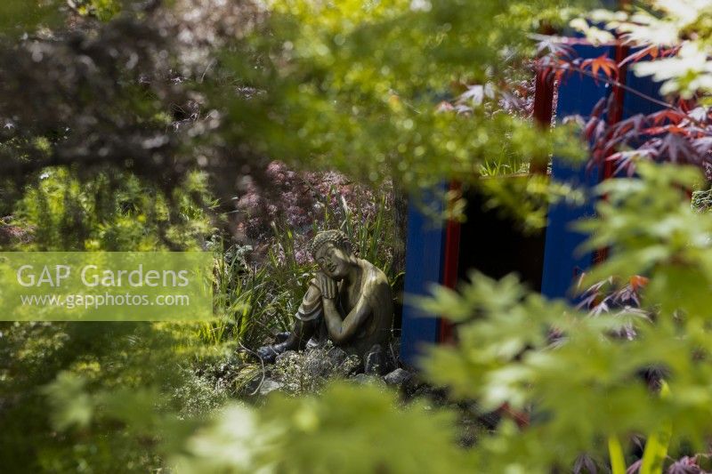 Le jardin japonais avec une réplique de salon de thé et une statue de bouddha au repos à côté de la maison de thé. Entouré d'érables japonais. Trago Mills montrent les jardins, Devon, Royaume-Uni. Peut. Printemps. Mise au point sélective.