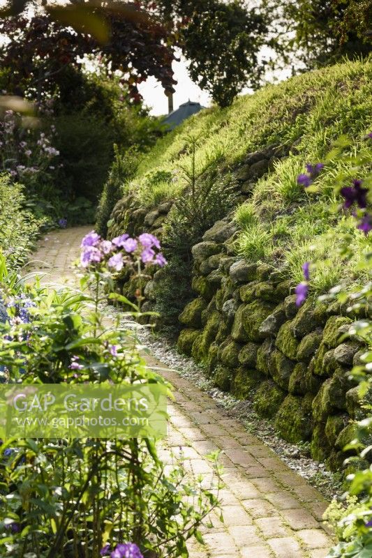 Chemin en briques longeant la limite du jardin formé par une colline fortifiée de l'âge du fer.