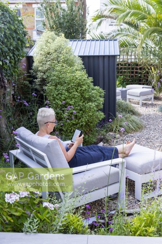 Propriétaire de jardin assis sur une chaise dans le jardin en train de lire