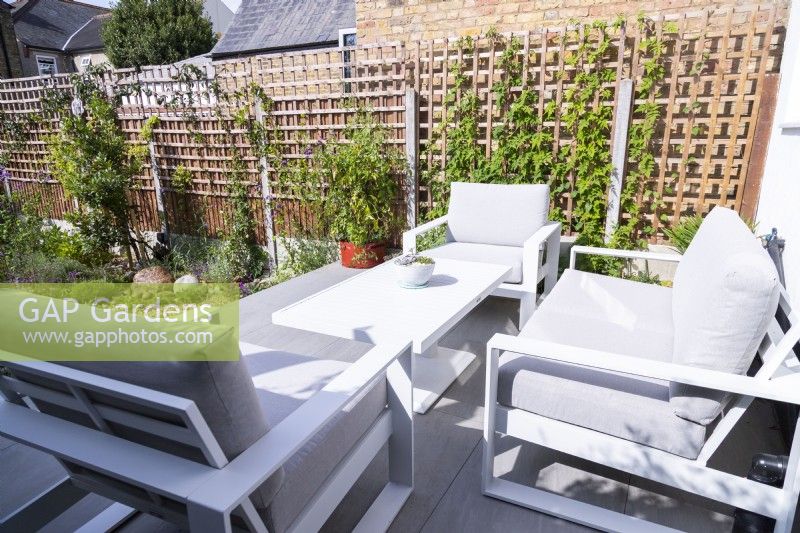 Table et chaises sur terrasse surélevée donnant sur jardin