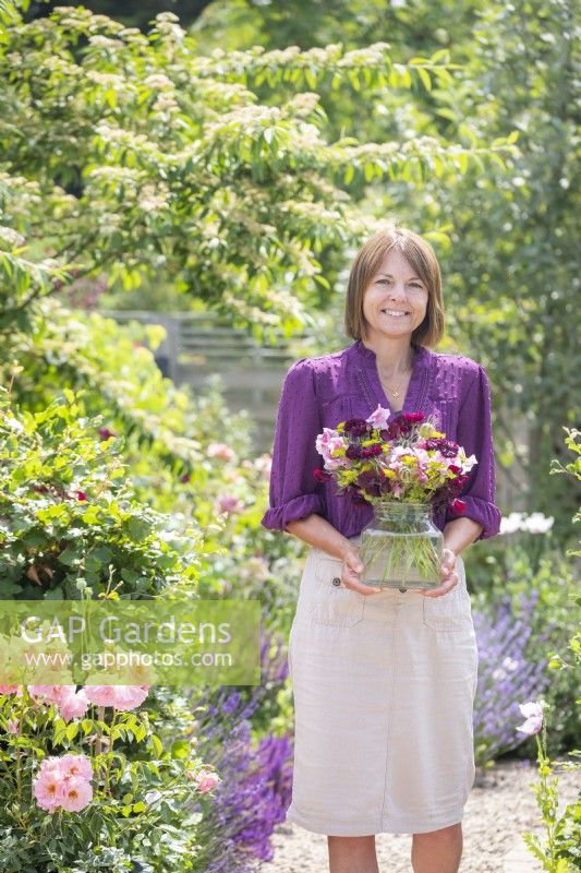 Femme portant un bouquet de fleurs dans un grand vase en verre