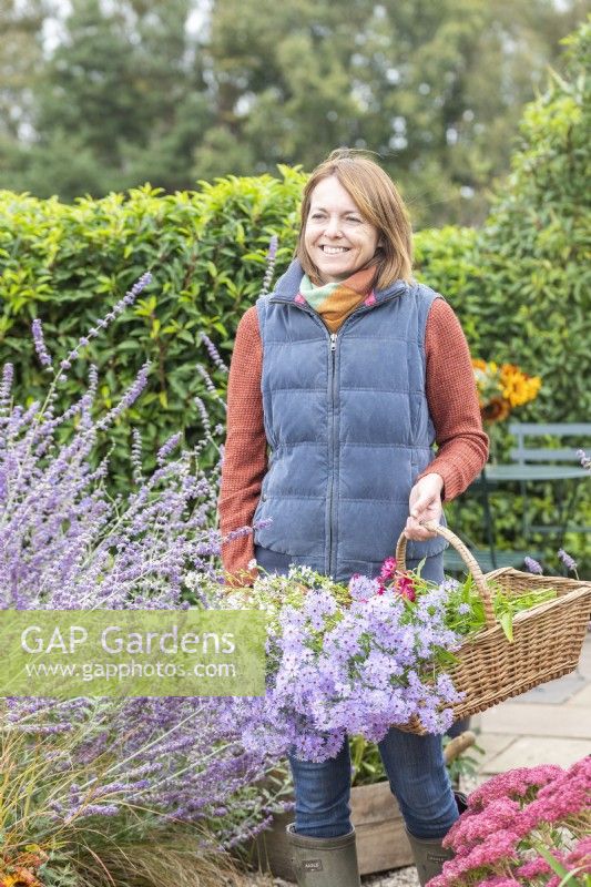 Femme marchant dans le jardin portant un panier d'Asters