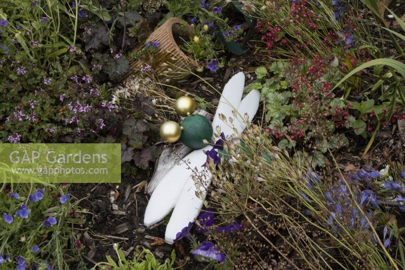 Une libellule fabriquée à partir de vieilles boules de Noël et de mousse d'emballage parmi une variété de plantes de jardin. Lumières du port, jardin Devon NGS. Juillet.