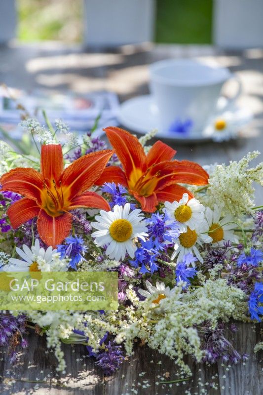 Bouquet de fleurs d'été contenant des marguerites, des bleuets, des hémérocalles, des grandes vergerettes et des persicaires.