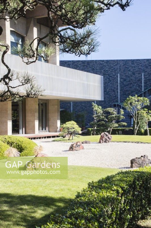 Gravier ratissé avec des roches placées connues sous le nom de karesansui avec des pins dans la zone appelée jardin de pierre. Vue sur l'hôtel.
