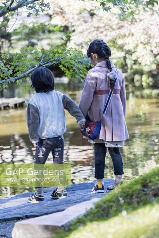 Frère et sœur japonais se tenant la main et regardant dans l'étang.
