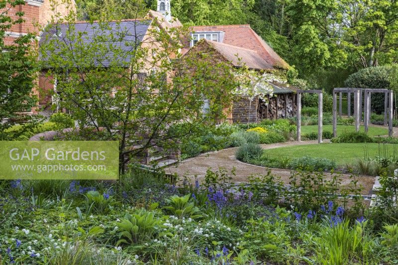 Un jardin contemporain aux couleurs du milieu de l’été est planté à l’est de la maison. Admirez un banc ombragé de jacinthes, de giroflées et de graminées.