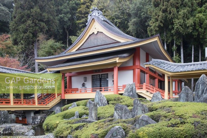 Vue sur le bâtiment du temple avec une zone de rochers, connue sous le nom d'ishigumi, placée dans un parterre de rhododendrons (pas en fleur) au premier plan.