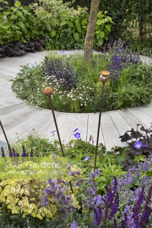 Sentier circulaire croisant des parterres de fleurs de plantes vivaces dans le jardin « Here We Go Round The Mulberry Bush » au BBC Gardener's World Live 2019, juin