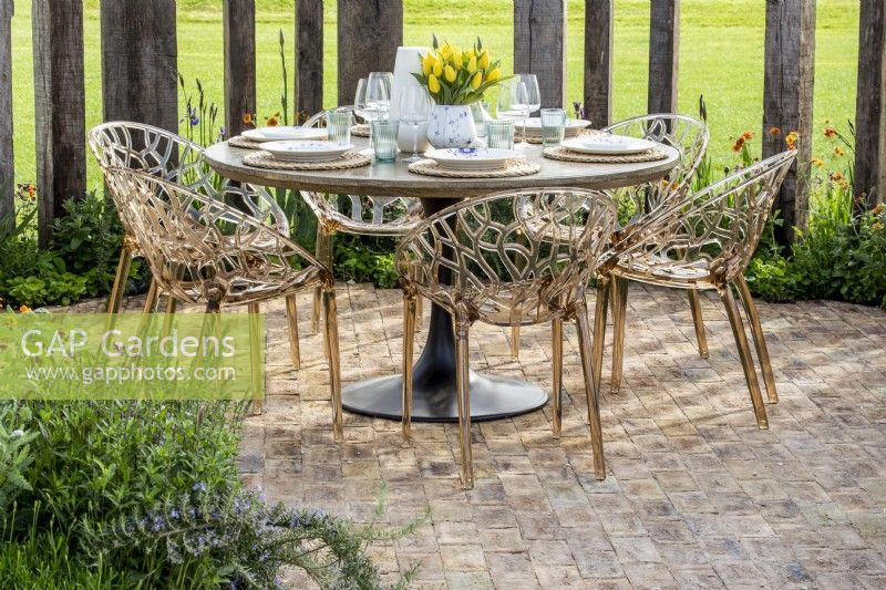 Chaises en plastique modernes et table à manger ronde aménagée sur un patio pavé de briques