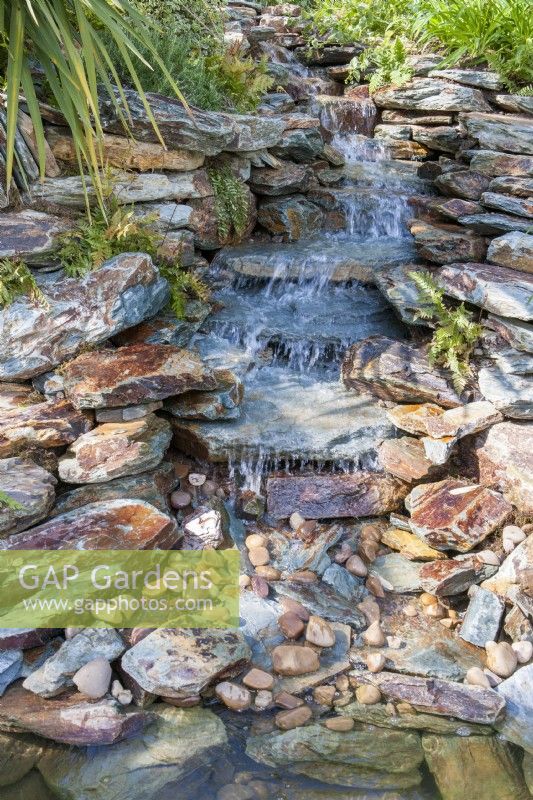 Un ruisseau tombant en cascade sur des rochers en pierre dans un étang 
