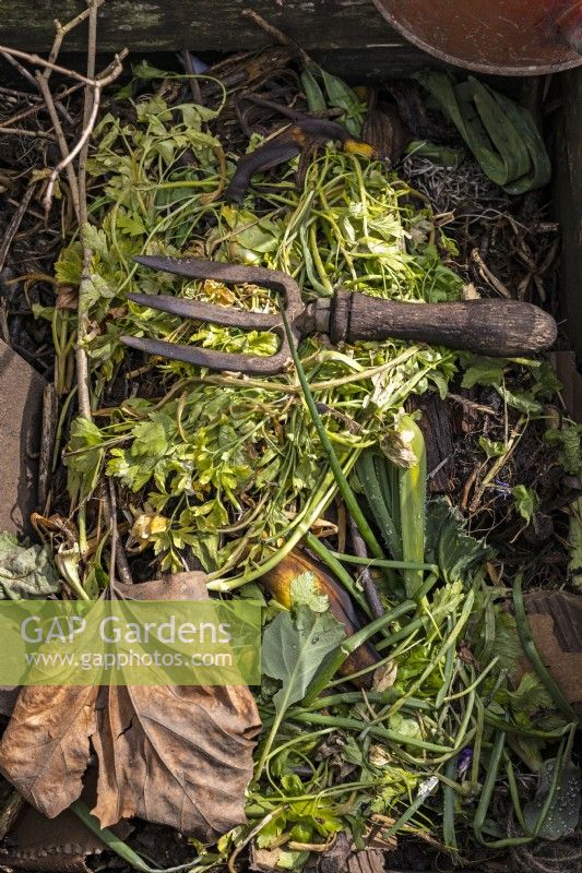 Bac à compost avec feuilles mortes, épluchures et compost et fourchette à main vintage 