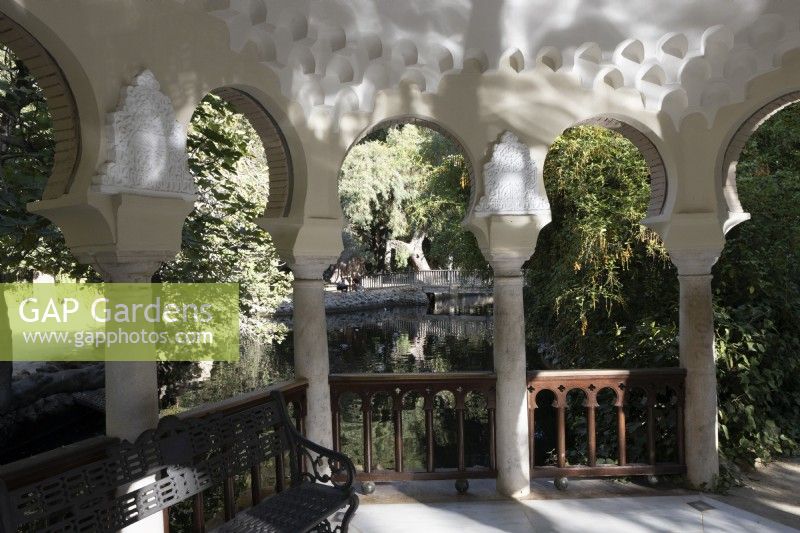 Vue depuis l'intérieur d'une pergola sur une île, en face d'un lac, avec des arches de style islamique. Parque de Maria Luisa, Séville, Espagne. Septembre 