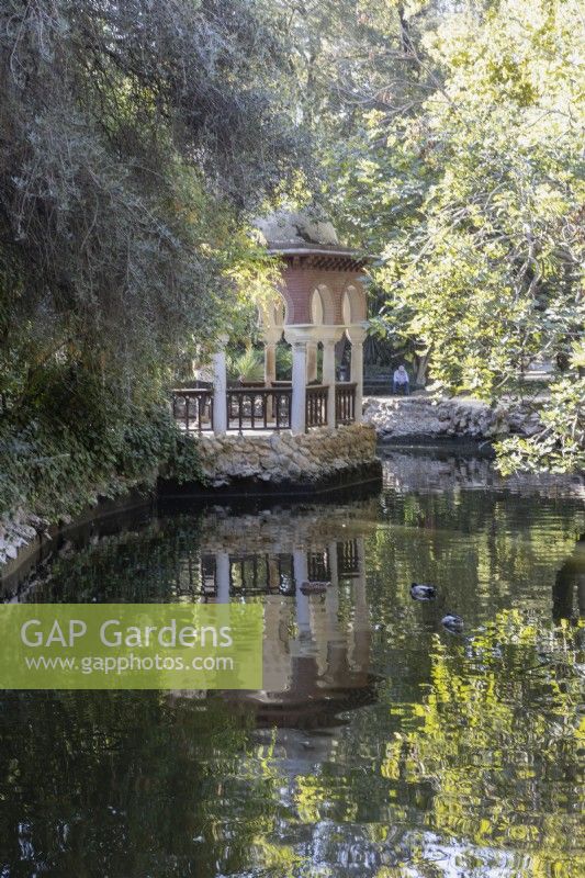 Donnant sur un lac jusqu'à une pergola ornée d'arches. Parque de Maria Luisa, Séville, Espagne. Septembre 