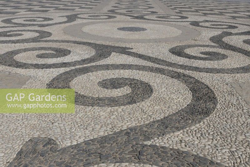 Un grand espace ouvert et plat est pavé de galets noirs et blancs et aménagé selon un motif symétrique et géométrique. Plaza de España, Parque de Maria Luisa, Séville, Espagne. Septembre 