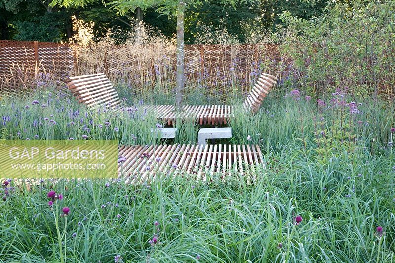 Jardin naturel avec chaise longue en bois, Stipa gigantea, Panicum Heavy Metal, Verbena bonariensis 
