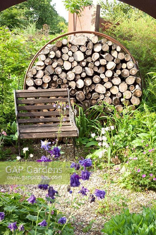 Sculpture de ferraille dans le jardin avec du bois de chauffage 