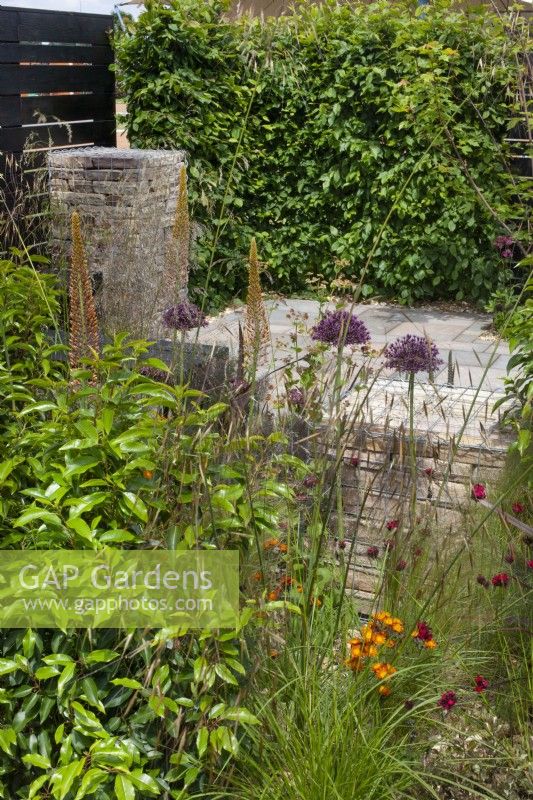Gabions remplis de briques entourés de plantes vivaces telles que des alliums, des eremurus et des graminées dans le jardin « Slow Burn » au BBC Gardener's World Live 2015, juin 