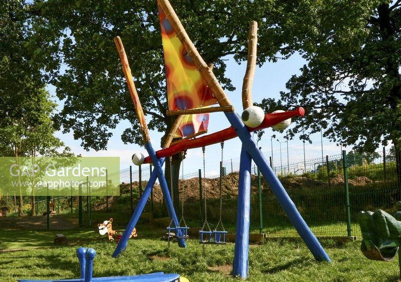 Balançoire en bois colorée pour enfants - libellule dans le jardin. 