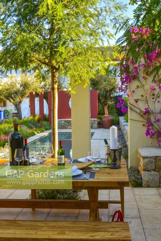 Table et banc en bois avec Acacia dans le patio donnant sur la piscine du jardin méditerranéen. JuinDesigner : Alan Rudden 