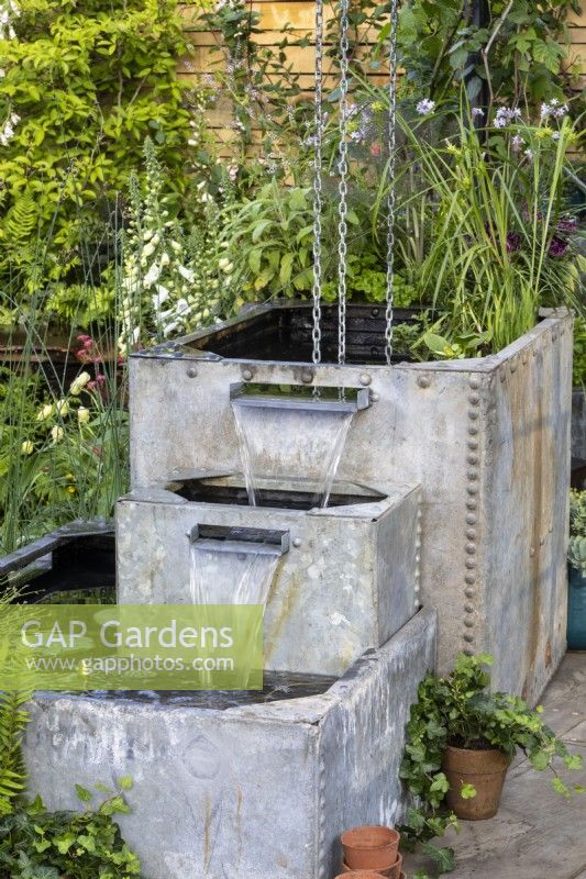 Des pots galvanisés récupérés sont utilisés comme système de collecte d'eau - 'Flood Re: The Flood Resilient Garden' - designers Naomi Slade et Ed Barsley - RHS Chelsea Flower Show 2024 
