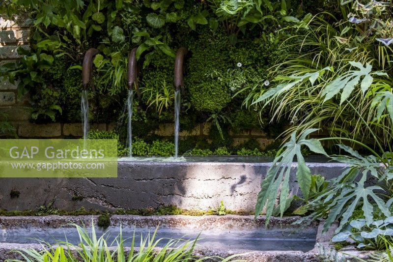 Trois tuyaux en cuivre circulant avec de l'eau dans un bassin étroit du jardin d'écothérapie : conçu par Tom Bannister 
