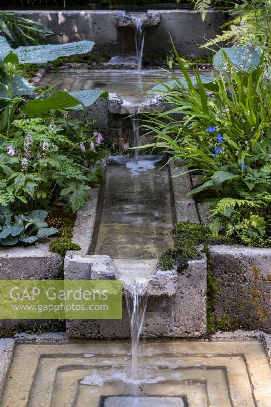 L'eau coule dans une série de goulottes, un ruisseau se jette dans une piscine carrée sur le jardin d'écothérapie : conçu par Tom Bannister 