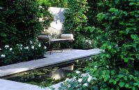 Jardin formel de rigole d'eau avec siège et haie en arc de charme et roses blanches. Chelsea FS 2002