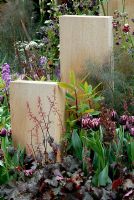 Heuchera 'Blackbird', Tulipa 'Cracker', Euphorbia 'Fireglow' et Foeniculum vulgare 'Purpureum' plantés à côté de piliers sculptés en chêne vert