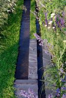 Ruisseaux d'eau bordés d'ardoise et de camomille et parterres de Salvia et d'Achillea dans le jardin 'Répétition et Différence'