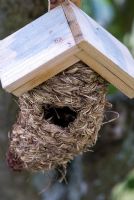 Nichoir tissé pour oiseaux en matériaux naturels avec toit en bois. École de conception de jardins de Lucy Redman, Rushbrook, Nr. Bury St. Edmunds, Suffolk.