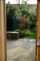 Avant de construire un nouveau patio dans un jardin urbain - Banc en béton et brise-vent partiellement construit - Jardin au-delà contenant Euonymus, Solanum jasminoides, Rosa 'Parade' et Miscanthus sinensis - Elmsdale Road, Londres