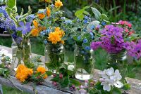 Pots en verre de fleurs de printemps cueillies dans le jardin, y compris Lunaria Annua - Honnêteté, Pulmonaria, Ancusa, Myosotis - Oubliez-moi, et Kerria Japonica - Juifs à la moelle. Vinca Major 'Elegantissima' fleur de pommier sur le banc.