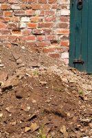 Tas de vieux gravats avec de vieilles briques, un sol pauvre et des racines en attente d'être enlevés pour faire place à un nouveau jardin