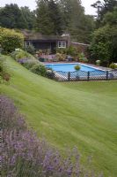 Regardant vers le bas de la pelouse fauchée vers la piscine contenue dans un petit jardin intérieur clôturé.