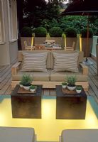 Terrasse en bois contemporaine avec éclairage au sol, tables de style oriental, canapé avec coussins et pots de sphères Buxus topiarisées - Kensington, Londres