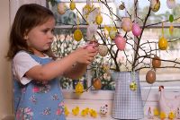 Petite fille suspendue des décorations de Pâques sur un arbre de Pâques à Pâques
