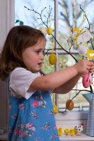 Petite fille suspendue des décorations de Pâques sur un arbre de Pâques à Pâques