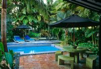 Jardin clos de cour avec piscine, chaises longues, parasols, chaises et tables et plantation tropicale - Key West, États-Unis