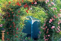 Une arche couverte de roses errantes menant à un pavillon