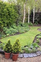 Pelouse de forme ovoïde simple dans un jardin bien entretenu au printemps avec des carreaux victoriens comme décoration