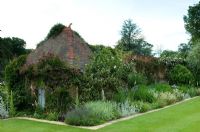 Bâtiment de jardin en briques et tuiles avec rosiers grimpants 'Veilchenblau' et parterre de fleurs herbacées - Mannington Hall, près de Norwich, Norfolk