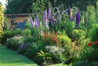 Les parterres de fleurs herbacées, avec Verbascum, Digitalis, Phygelius, Papaver, Campanula et géraniums rustiques - The Abbey House, Wiltshire