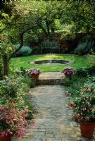 Petit jardin clos de ville avec pelouse hexagonale, plan d'eau et chemin de granit. Pots avec Fuchsias et Impatiens - Londres