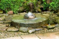 Caractéristique de l'eau de meule entourée de fougères, de gravier et de roches - Hunmanby Grange, Yorkshire